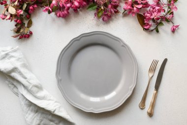 Beyaz masanın üzerinde çiçek açan elma çiçekleri olan zarif masa ayarı.