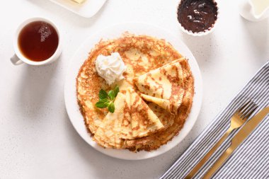 İnce krepli Rus kahvaltısı ya da çikolatalı blini ve beyaz üzerine çay. Üst görünüm.
