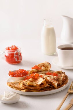 Beyaz üzerinde kırmızı havyar olan ince Rus krepleri ya da blini. Shrovetide. Kapatın. Dikey biçim.
