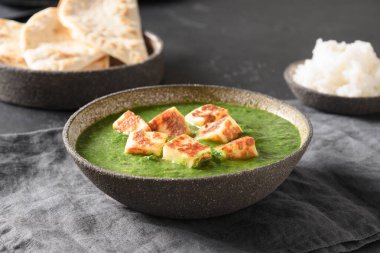 Palak Paneer gri arka planda basmati pilavı servis etti.