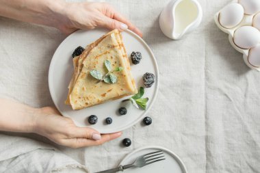 Kadın lezzetli Rus gözlemelerinden ya da blinilerden oluşan kahvaltı servisi yapıyordu. Yukarıdan görüntüle.