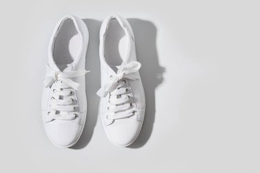 Gri arka planda, fotokopi alanı olan beyaz ayakkabılar. Yıkama ve temizlik konsepti. Ayakkabılara dikkat et. Üst görünüm.