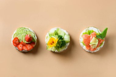 Farklı tiplerde pirinç kekleri bej arka planda garnitür meyveleri, sebzeler, mikroyeşiller. Şenlik partisi için sağlıklı renkli yemekler..