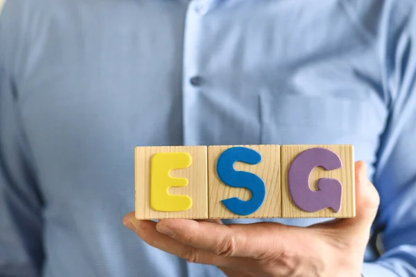 Wooden blocks with abbreviation ESG in hands.