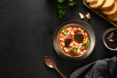 İspanyol asturiana fabada. Siyah arka planda sucuk ve morcilla..