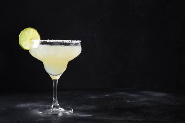 Klasik Margarita kokteyli. Siyah arka planda limon suyu ve buz var..