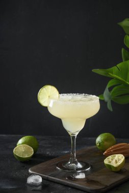 Limon suyu ve buzlu siyah arkaplanlı klasik Margarita kokteyli. Dikey yönelim.