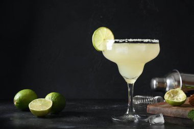 Koyu siyah zemin üzerinde limon suyu ve buz küpü olan klasik Margarita kokteyli..