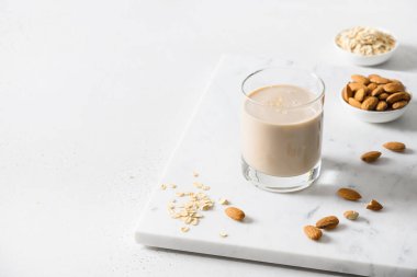 Beyaz arka planda badem ve yulaf ezmesi sütü. Kapat..