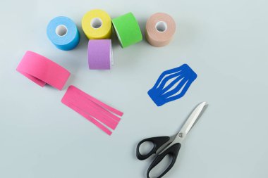 Mavi arkaplanda üç rulo kineziyoloji bandı.