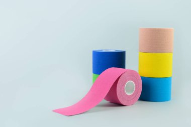 Mavi arkaplanda üç rulo kineziyoloji bandı.