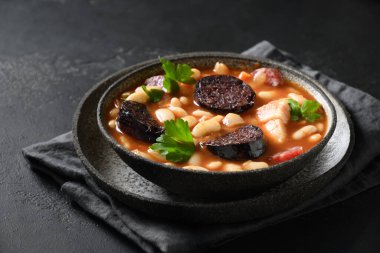 İspanyol asturiana fabada. Siyah arka planda sucuk ve morcilla..