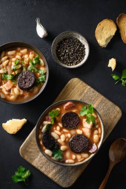 İspanyol asturiana fabada. Siyah arka planda sucuk ve morcilla..