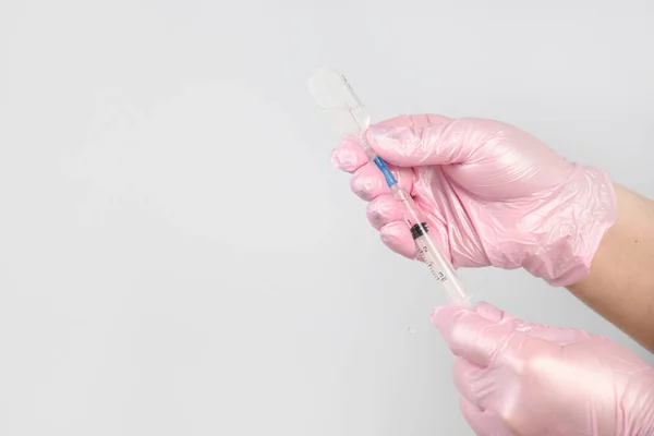 Female hands in pink gloves fill a syringe for medical procedure or beauty injection.