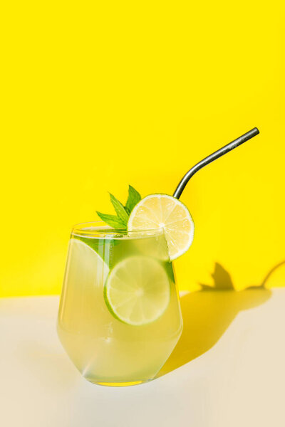 Летний лимонад с лаймом и мятой на желтом солнечном фоне. Закрыть.