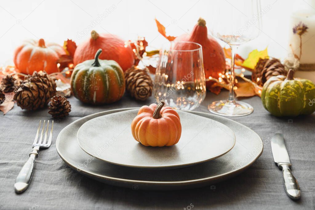 Halloween and Thanksgiving day dinner decorated fallen leaves, pumpkins, spices, grey plate. Close up.