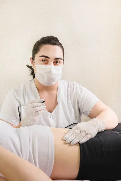 Arzt ist bereit für Haarentfernung am Bauch von Frauen mittels Elektroepilation. — Stockfoto