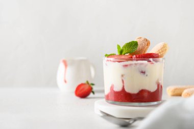 Cam kavanozlara katılmış tatlı içinde kurabiye savoyardi, mascarpone ve krem şantili çilek.