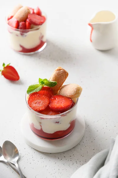 Postre en capas en frascos de vidrio con galletas savoyardi, mascarpone y crema batida decorado fresas — Foto de Stock