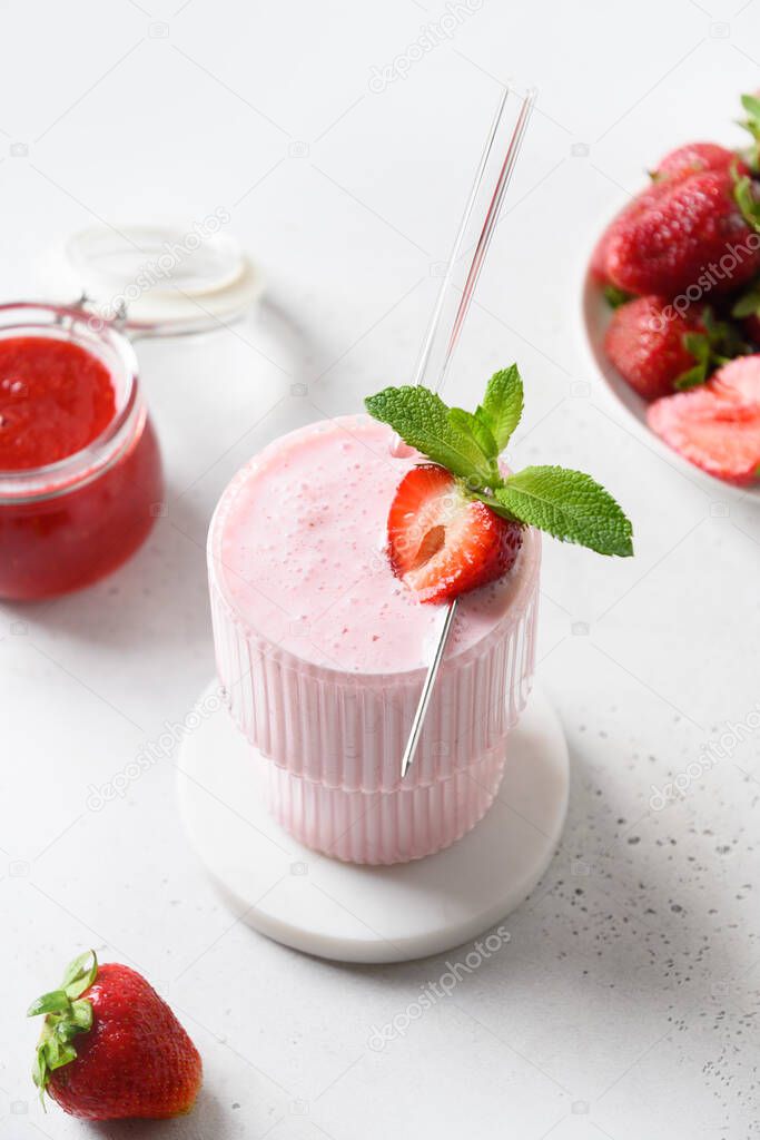 Strawberry lassi, smoothie or milkshake on a white background. Vertical format. Close up. Healthy dairy Indian beverage. Non-alcoholic children's dessert.