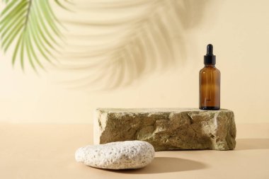 Minimum modern SPA kompozisyonu, cam şişedeki kozmetik yağla taşın üzerine koyulmuş ve gölgesi tarafsız bej arka planda..