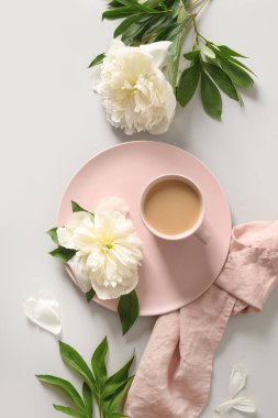 Kahve fincanı ve gri ofis masasında beyaz şakayık çiçekleri olan romantik yaz kahvaltısı..