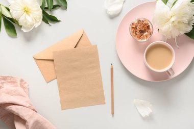 Kahve fincanı ve gri ofis masasında beyaz şakayık çiçekleri olan romantik yaz kahvaltısı. Yukarıdan bak, düz yat. Zarif harfleri kavra. Tebrik kartı.