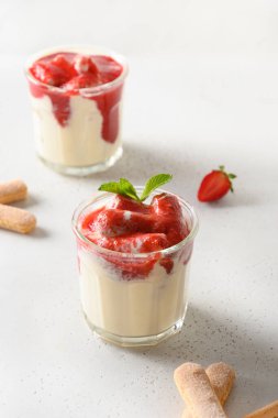 Cam kavanozlara katılmış tatlı içinde kurabiye savoyardi, mascarpone ve krem şantili çilek.