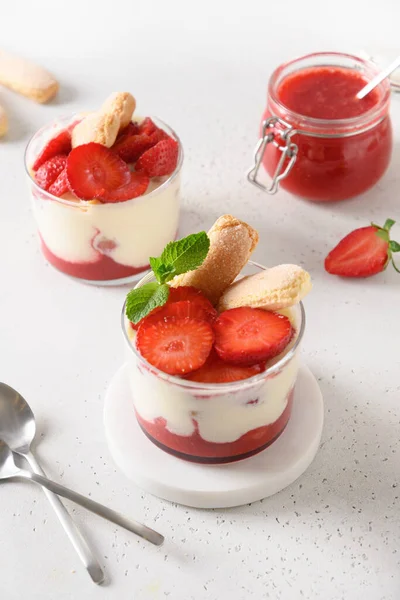 Cam kavanozlara katılmış tatlı içinde kurabiye savoyardi, mascarpone ve krem şantili çilek.