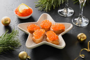 Noel için siyah arka planda kırmızı havyarlı Rus aperatifi kanepesi.