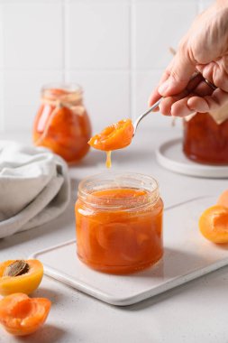 Ev yapımı kayısı reçeli kaşık içinde kadınların elinde.