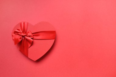 Kırmızıda kırmızı fiyonklu kalp şeklinde hediye kutusu. Üst Manzara. Metin için boşluk.