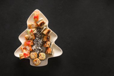 Noel ağacı olarak hazırlanmış suşi, siyah köknar dalları ile süslenmiştir..