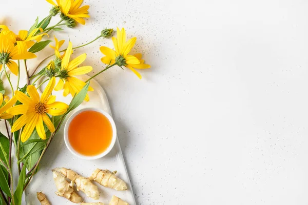 Jerusalem artichoke syrup in bowl, flowers and root. — Stock Photo, Image