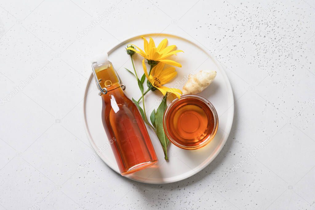 Jerusalem artichoke syrup in bottle, flowers and root.