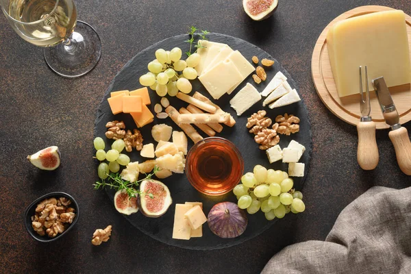 Assiette au fromage avec raisins, noix, figues sur fond brun. Vue du dessus. — Photo