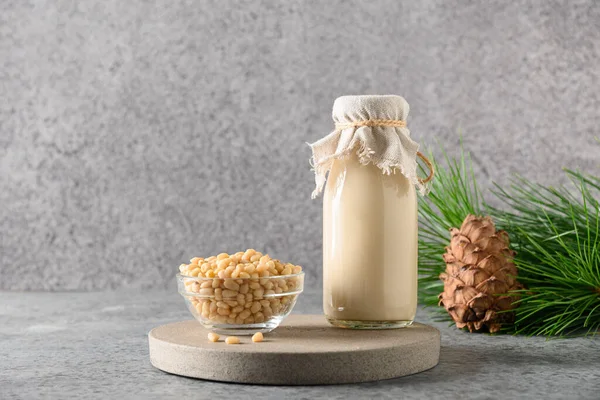 Vegane Zedernussmilch in der Flasche auf grauem Hintergrund. Alternative Milch. Gesunder veganer Drink. — Stockfoto