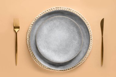 Zarif masa seti, boş gri tabak, altın çatal bıçak seti bej sonbahar masasının modeli. Üst görünüm.