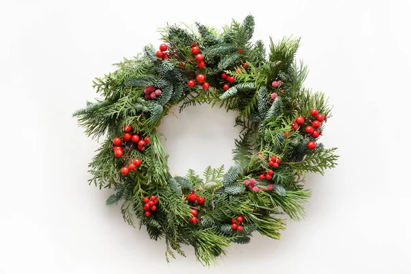 Kırmızı kutsal böğürtlenli taze doğal ladin dallarından oluşan bir Noel çelengi. Xmas için geleneksel dekorasyon.