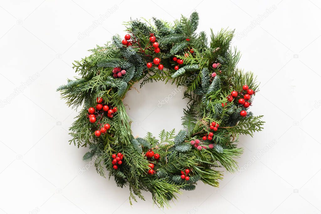 Festive Christmas wreath of fresh natural spruce branches with red holly berries. Traditional decoration for Xmas.