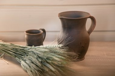 Kil sürahi ve buğday bir buket ile masada bir fincan. clayware