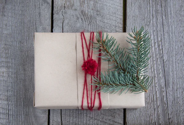 Coffret cadeau de Noël sur table, emballage artisanal, parchemin, branches de sapin, mignon cadeau simple de dernière minute fait à la main. Vue du dessus . — Photo