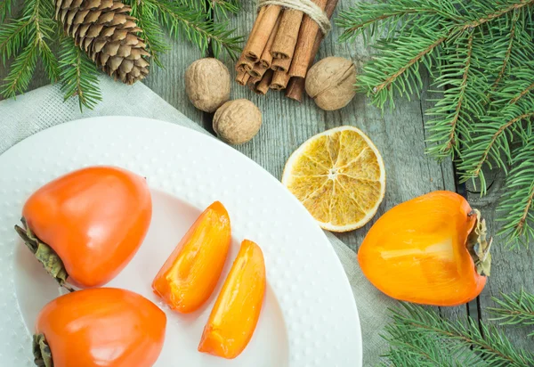 Bodegón de Navidad con caqui fresco con pino sobre fondo de madera. Vista superior . —  Fotos de Stock