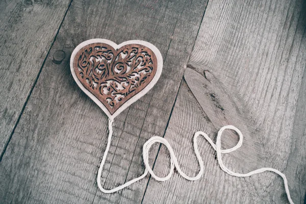Corazón tallado de madera del día de San Valentín sobre fondo de tabla de madera con espacio de copia . — Foto de Stock