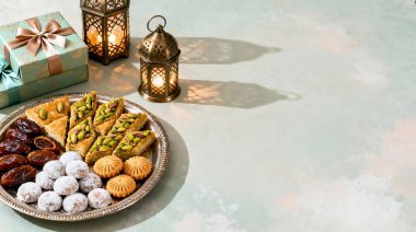 Dekoratif bir tepside geleneksel Orta Doğu tatlıları ve hamur işleri, hediyeler ve fenerler eşliğinde, kutlamalar ve toplantılar için mükemmel..