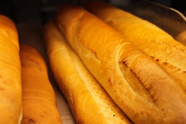 Fresh juicy breads from the oven. White flour bread in the store - photo. Unhealthy but delicious pastries.
