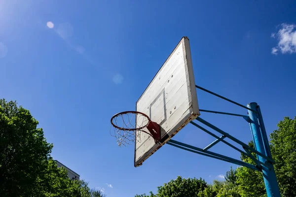 Basketball hoop against the blue sunny sky - photo. School sports equipment, court for competitions. December 21 Basketball day, birthday