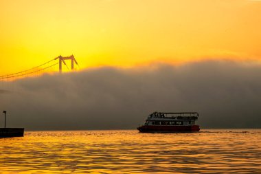 Foggy and Misty scene of Bosphorus Bridge. Bridge over the Bosphorus in Istanbul. View from the Asian part of Istanbul. A boat in the fog