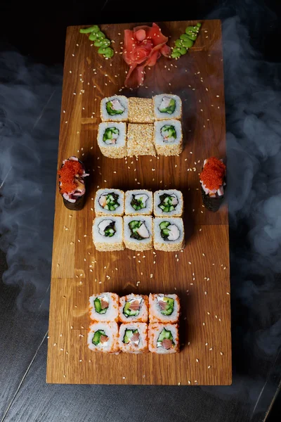 Koyu arka plan üzerinde ahşap bir gemide suşi rulo