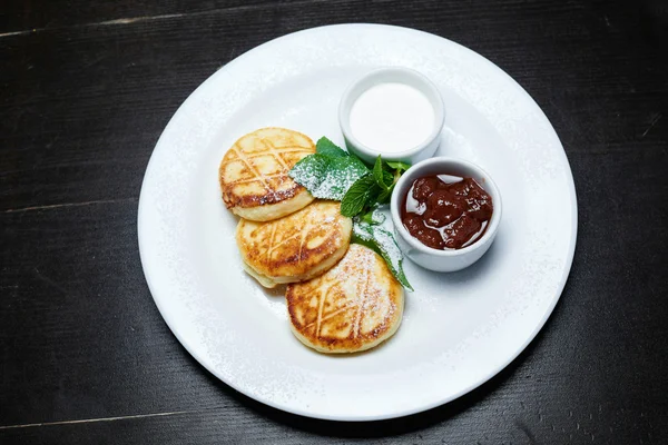 Cheesecake nane ekşi krema ve koyu arka plan üzerinde çilek sosu ile